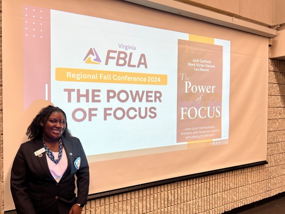 Student standing in from on a screen that says FBLA Regional Fall Conference 2024