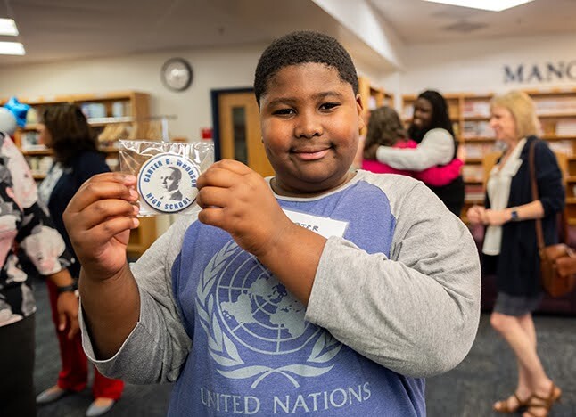 Student holds up a cookie and smiles