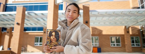 student holding up the movie that they were in