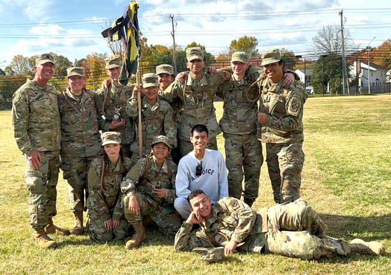 JROTC students dressed in camo posing for a picture on grass