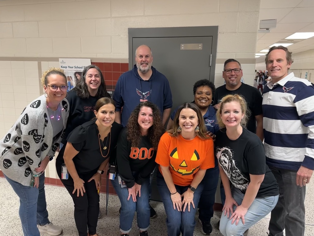 10 adults standing in a hallway with Halloween shirts