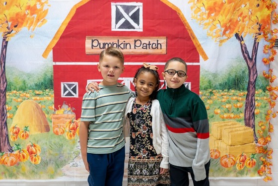 young students smiling in front of a small mural