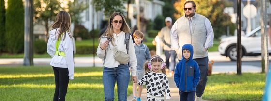 family walking to school together on a sidewalk