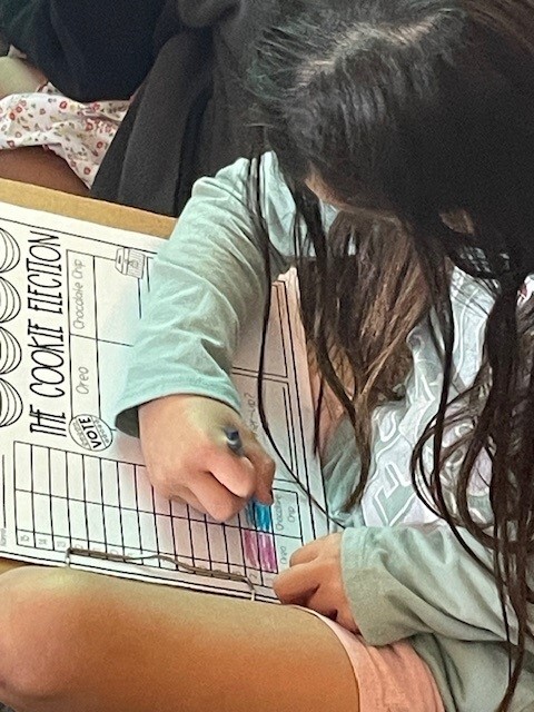 Student recording the votes for favorite cookies