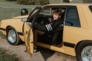 student sitting in a yellow car