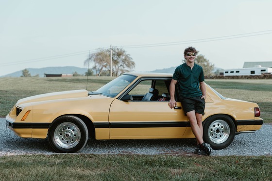 student leaning against yellow car