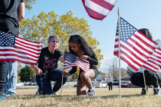 teacher and student planting American flags into the grass