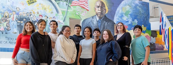 students smile below a mural