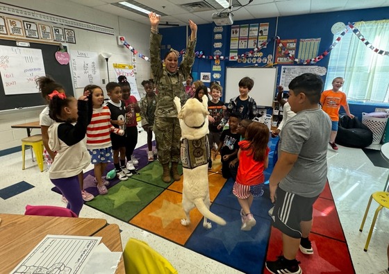 Military parents visiting classroom, including a service dog