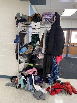 A rack filled with lost and found clothes and other items