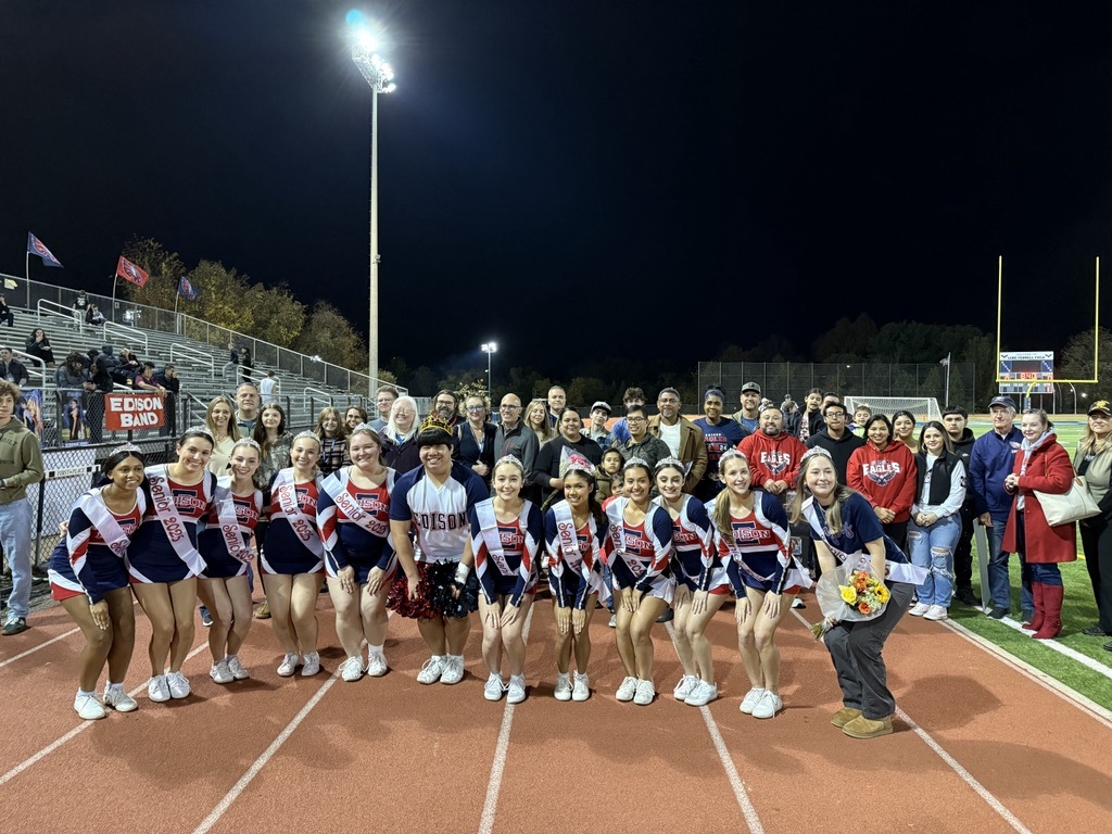 cheer leaders with tiaras and senior sashes standing on the track in from of their parents