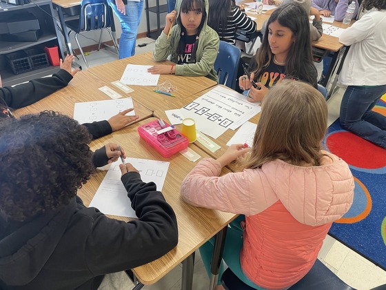 5th grade students gathered around to complete a math task 