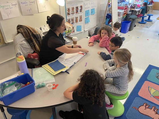 Students gather around the table to count with their teacher 