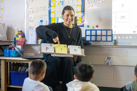 teacher points to a letter while students look at her