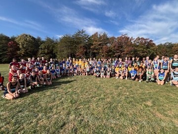 Middle School cross country athletes sitting and standing in group on field