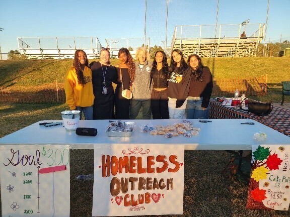 Group of students standing together behind table