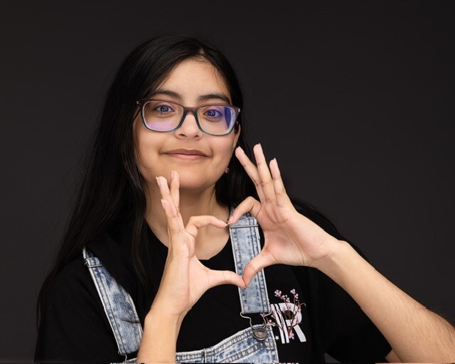 a girl with glasses making a heart with her hand