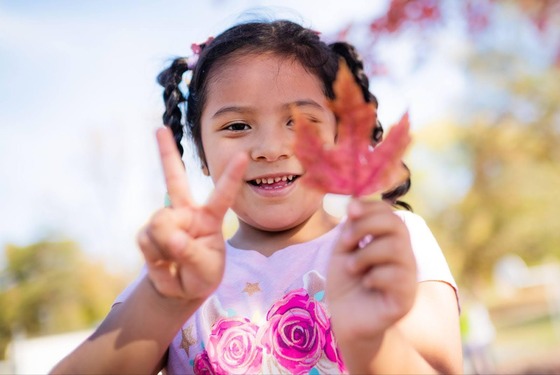 student holding up a leaf and smiling