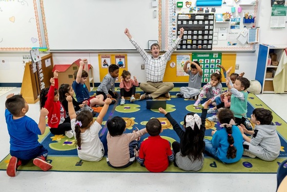 teacher and students sitting on rug during a lesson