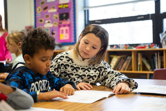 sixth grade student helps a younger student read