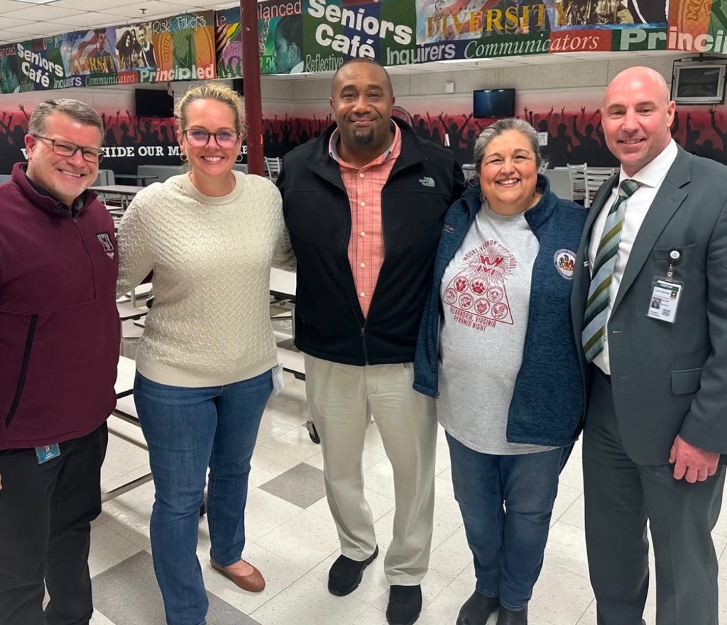 5 adults standing in a hallway smiling