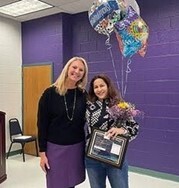 Principal Dr. Amy Goodloe standing with French teacher Elaine Gonzalez who is holding balloons and framed certificate