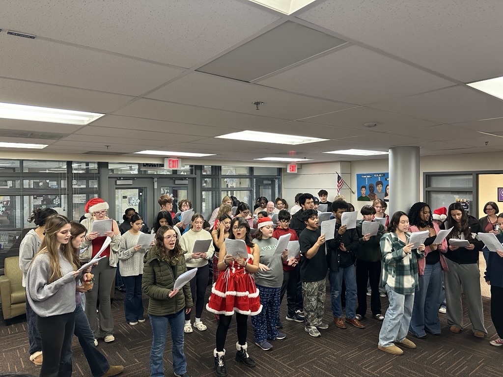 many students standing in the main office singing