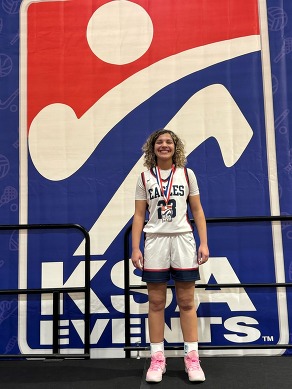 a girls basketball player standing on a stage with a metal around her neck