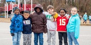 students smile in their winter jackets on the blacktop