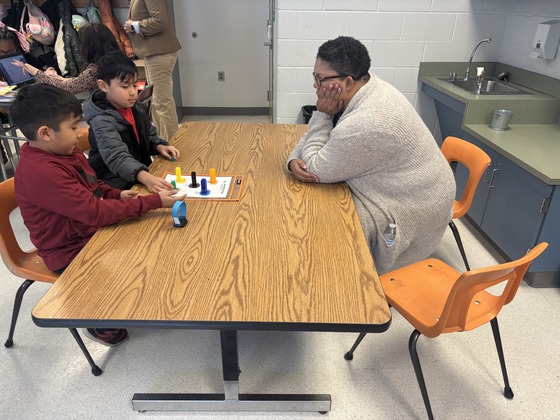 A teacher sits with two students 