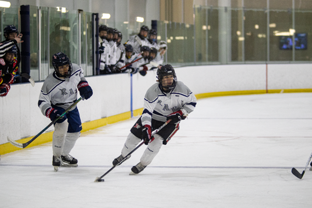 Woodson ice hockey player moving the puck down the ice