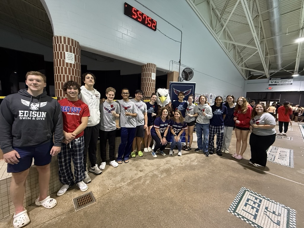 students standing in a line posing for a photo on a pool deck