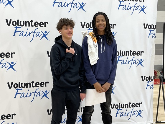 2 students standing in front of a sign that says Volunteer Fairfax