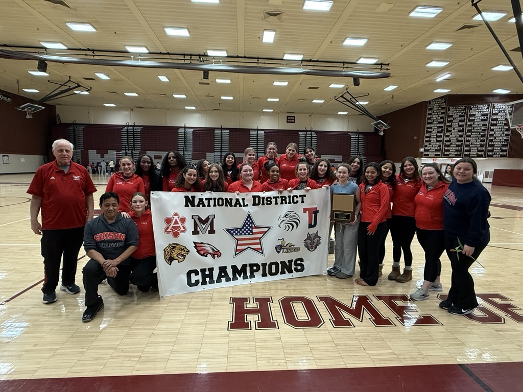 gymnasts standing behind a banner that says national district champions