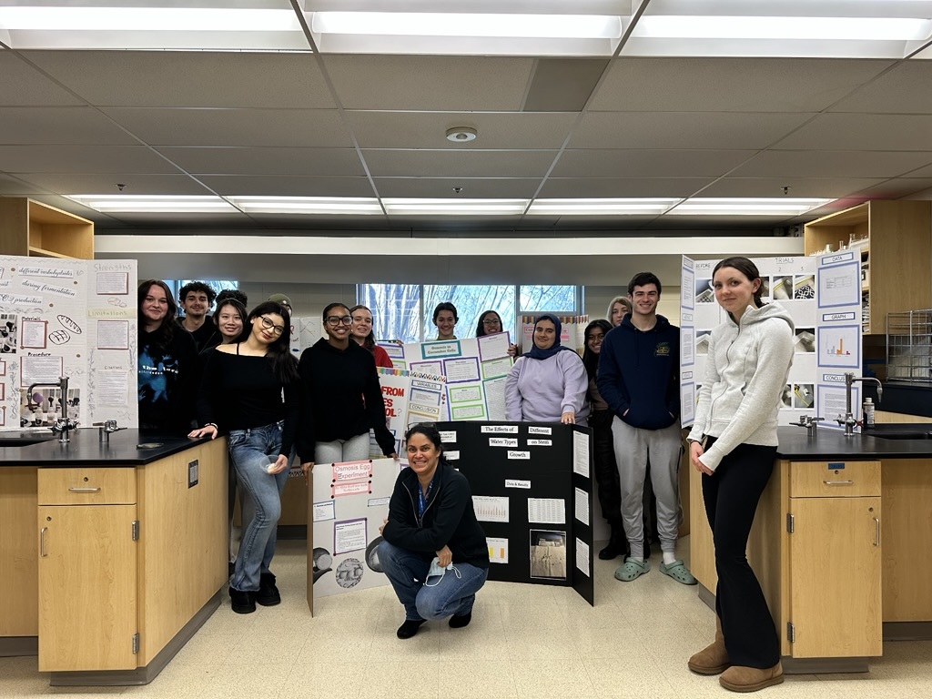 students standing in a science classroom with their science fair boards
