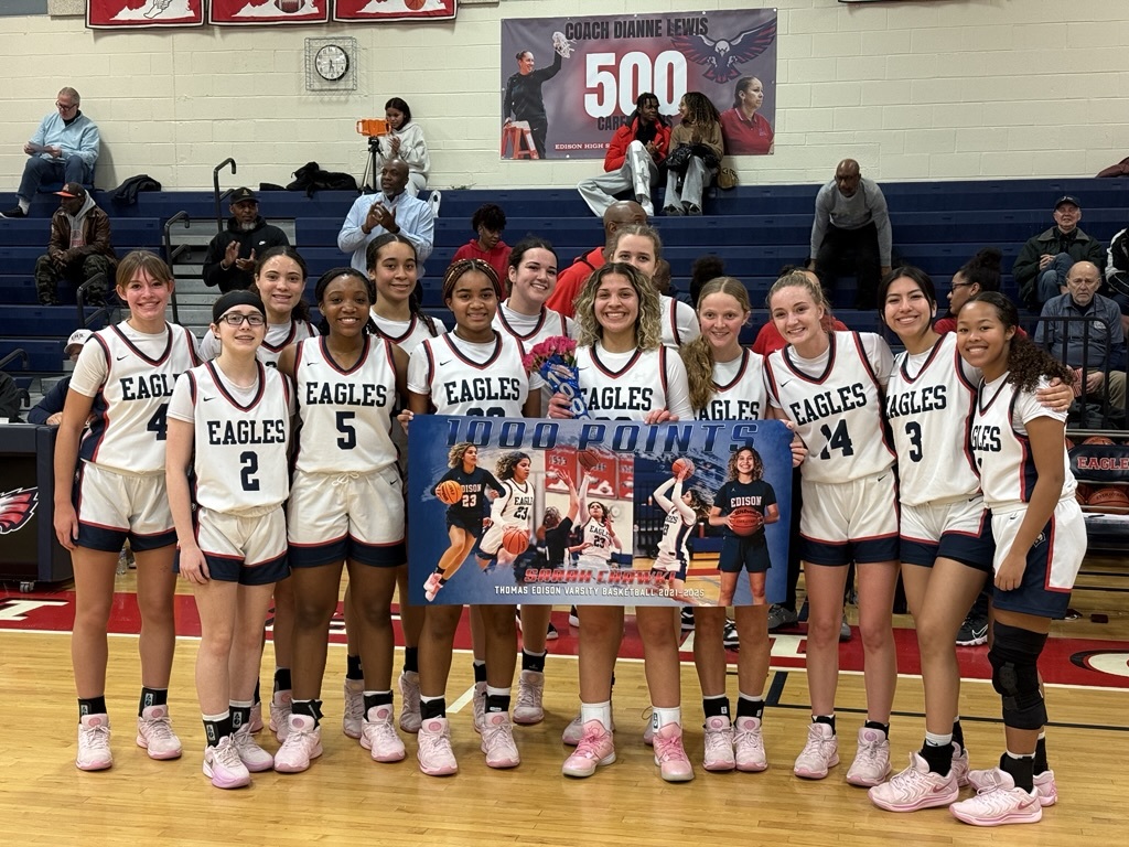 girls basketball players standing behind a banner that says 1000 points