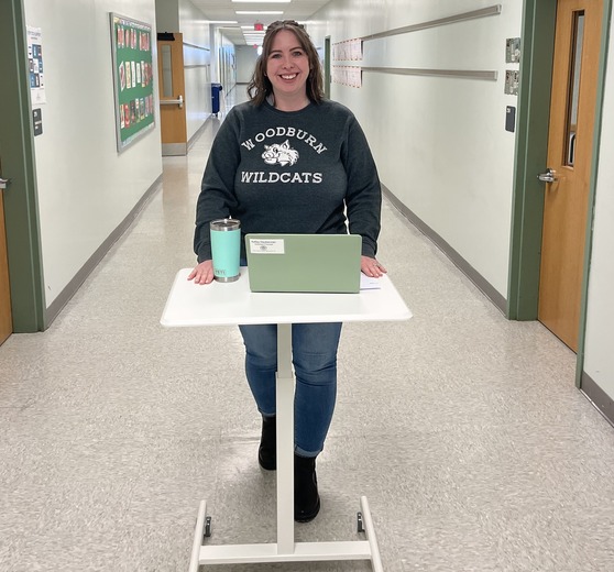 Ms. Dauberman walking in the hall with a standing desk 