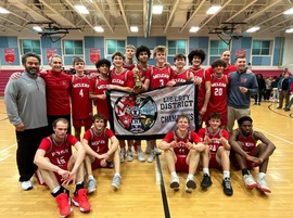 A basketball team in red jerseys with "MCLEAN" across the front stands and sits in a gym, holding a "LIBERTY DISTRICT CHAMPIONS" banner.