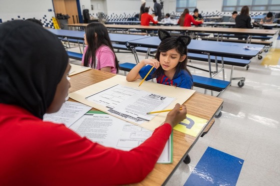 student sits at a table working on classwork