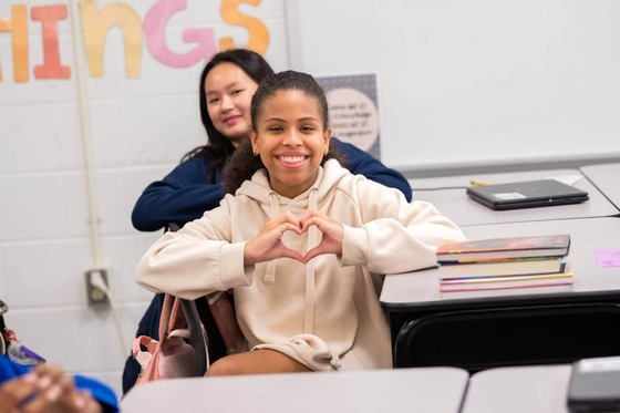 students smiling and holding a hand heart