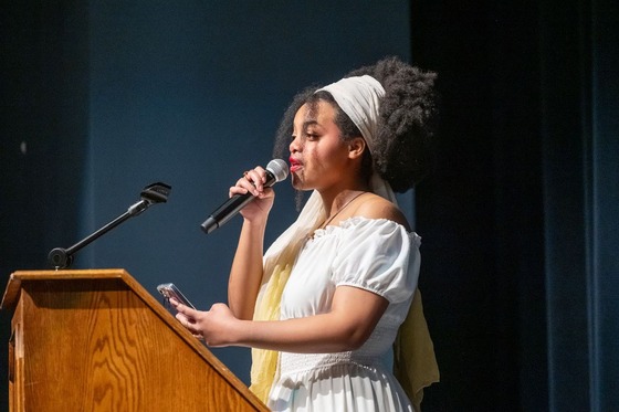 student speaks into a microphone on stage
