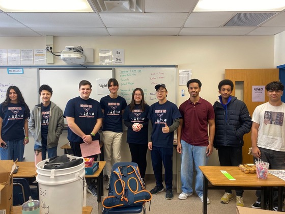 9 students standing in a classroom in a row