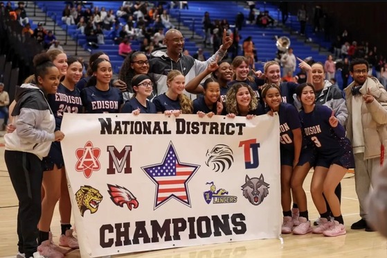 girls basketball players standing behind a banner that says national district champions