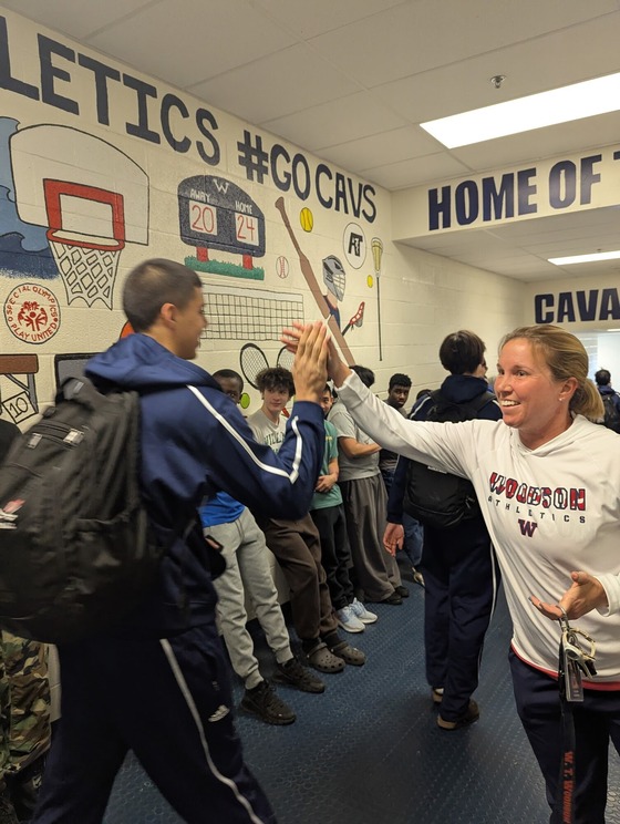 Teacher high fives woodson boys basketball player as they leave for States