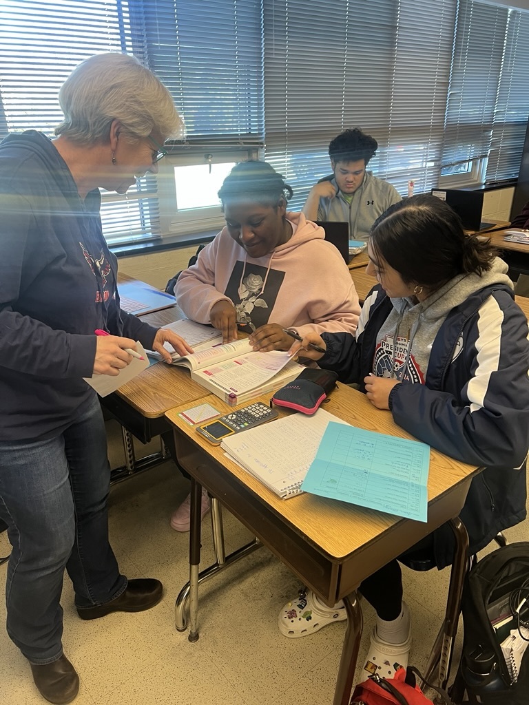 a teacher helping students reading a textbook