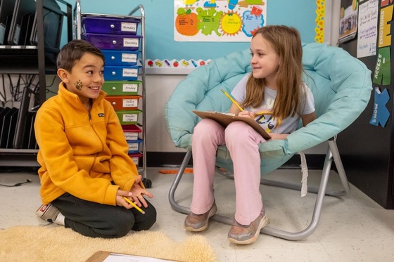 students smiling at each other while seated and reading