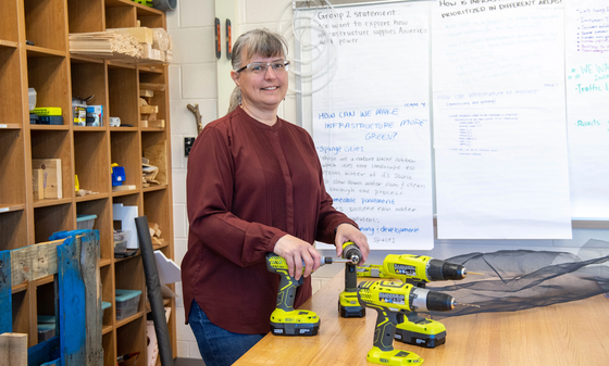 teacher smiles next to their power tools