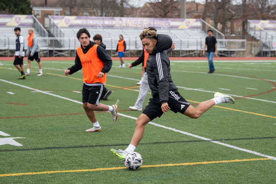 student kicking a soccer ball
