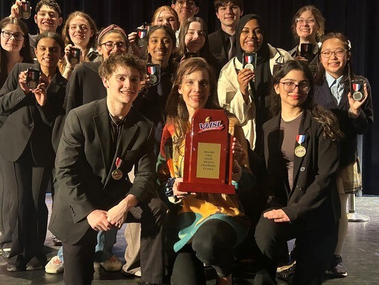Coach and students standing together holding trophy