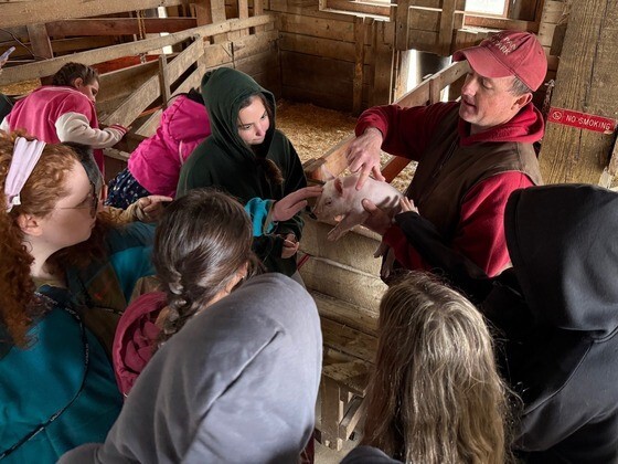 Students standing in group petting piglet